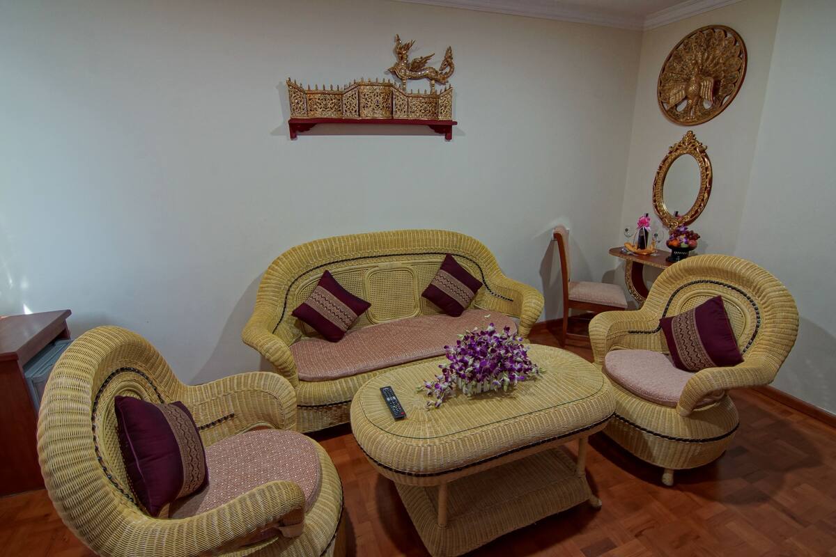 A living room with wicker furniture, a decorative shelf, and wall art.