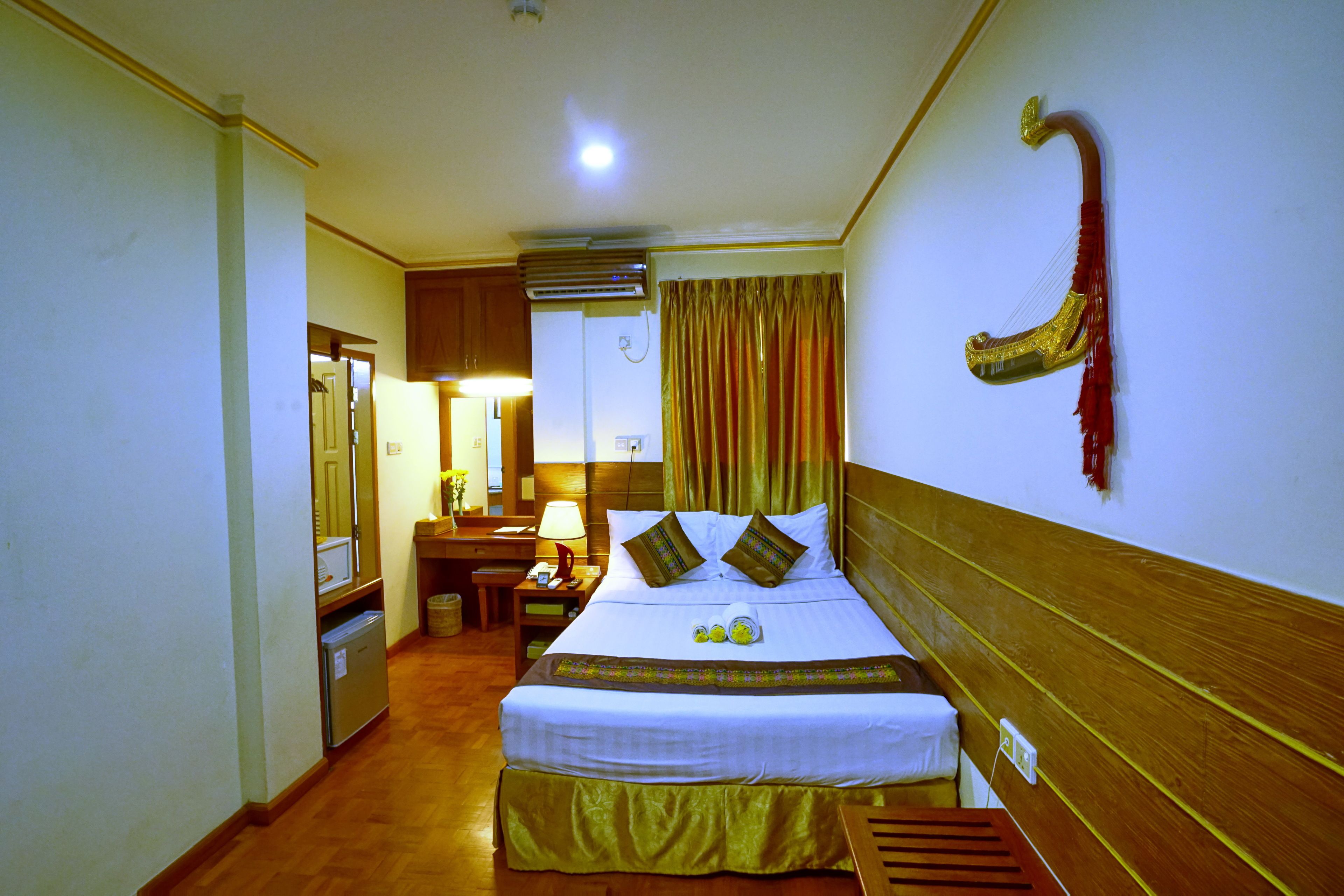 A hotel room with a bed, bedside table, lamp, and a wall-mounted decorative item.