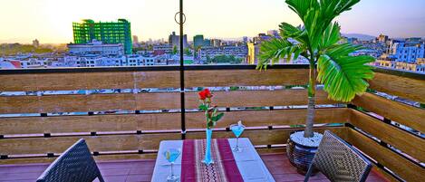 Terraza en la azotea con una mesa para dos, una sombrilla roja y vistas panorámicas de la ciudad.