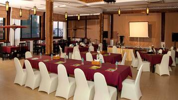 A conference room with tables set for a meeting, white chairs, and a projector screen.