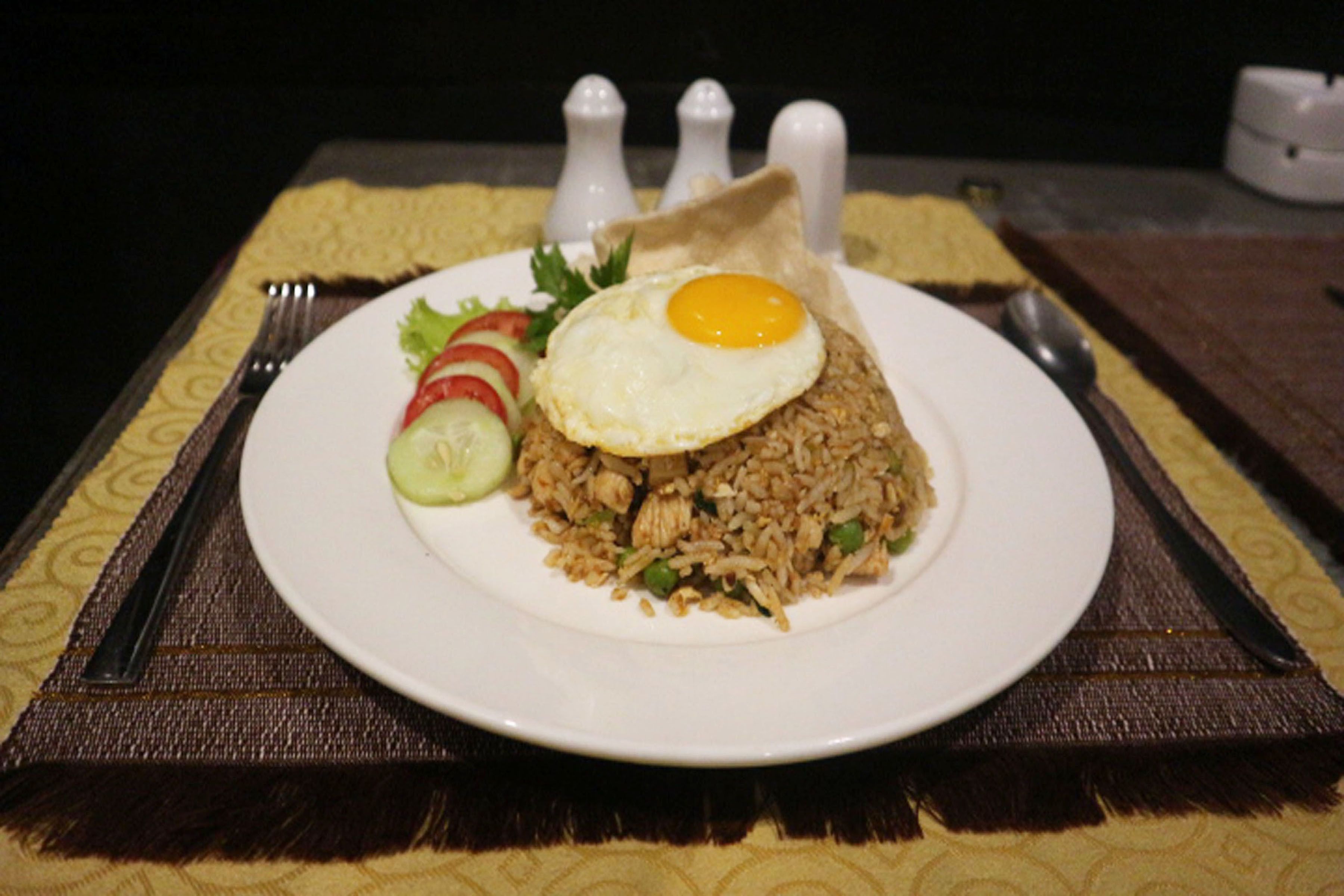 Une assiette de riz frit, garnie d’un œuf, le tout servi dans une assiette blanche.