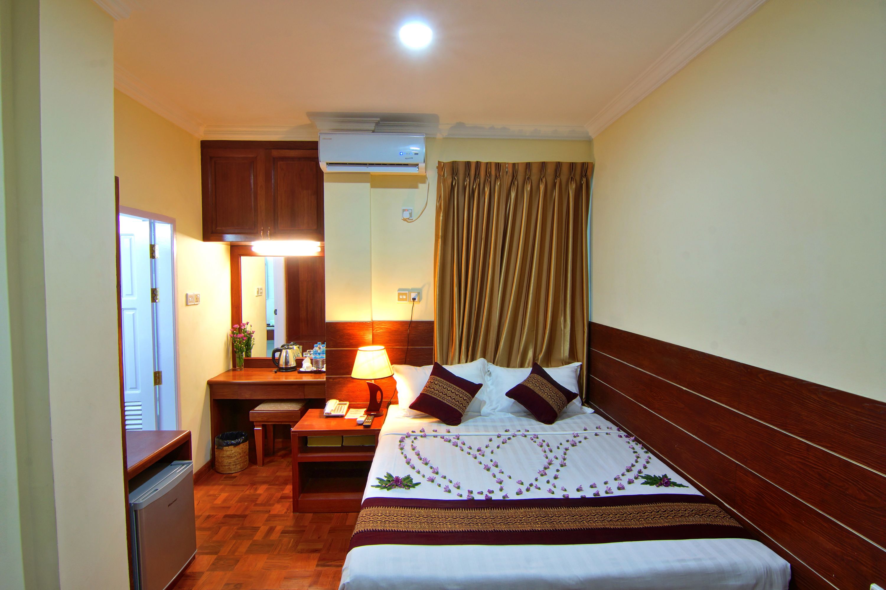 A hotel room with a bed, bedside table, lamp, and a small desk with a telephone.
