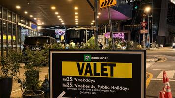 A parking sign for Valet Car Service with pricing details and payment options.