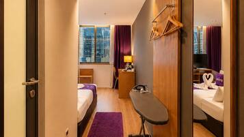 A hotel room with a bed, a desk, a mirror, a window with curtains, and a city view.