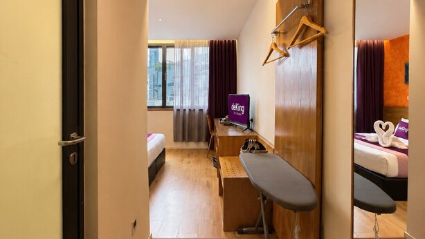 A hotel room with a bed, desk, chair, and a mirror. - deKing Hotel Twin Towers KLCC (Kuala Lumpur)