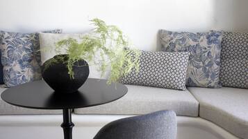 A modern living room with a round black table, a grey sofa, and patterned cushions.