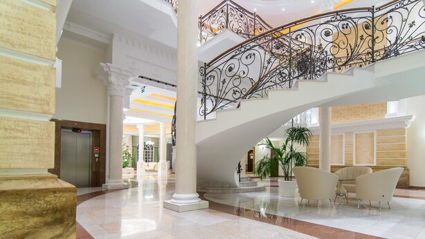 Eine großzügige Lobby mit einer imposanten Treppe, Marmorböden und einer Sitzecke.