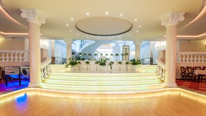 Eine großzügige Lobby mit einer zentralen Treppe, weißen Säulen und Blick ins Freie.