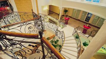 Una gran escalera con barandales de metal ornamentados y un suelo de mármol pulido.