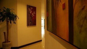 Ein Flur mit einem Blumentopf, einem Gemälde und einem großen abstrakten Kunstwerk an der Wand.