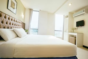 A hotel room with a large bed, a television, and a desk with a chair. - Mangga Boutique Hotel (Seri Kembangan)