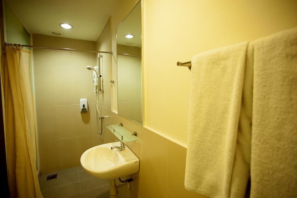 Un baño con lavabo, espejo, ducha y perchero para toallas.