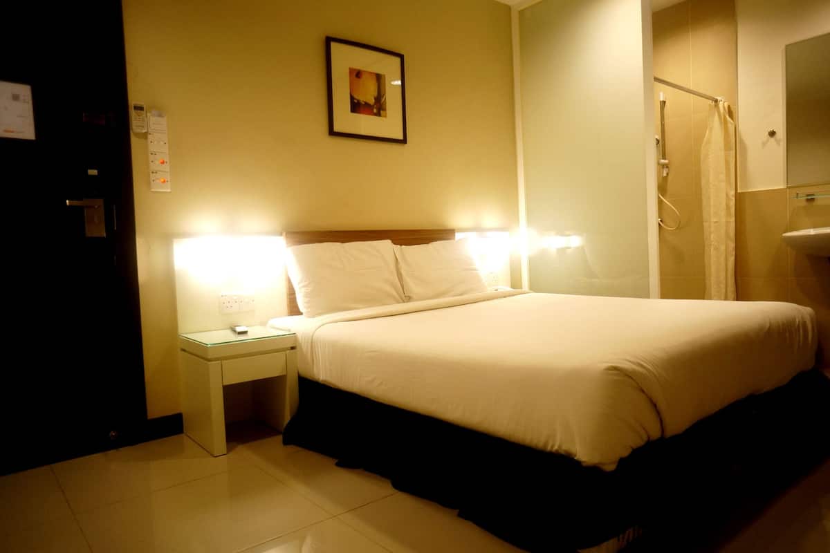 Hotelkamer met een bed, nachtlampjes, een nachtkastje, een lijst met afbeelding aan de muur en een douche.
