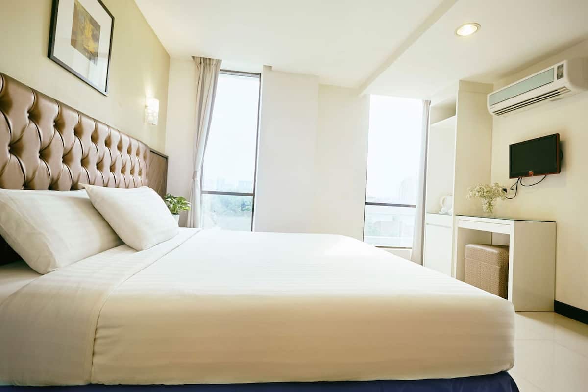 Een hotelkamer met een groot bed, een bureau, een televisie en een raam met gordijnen.