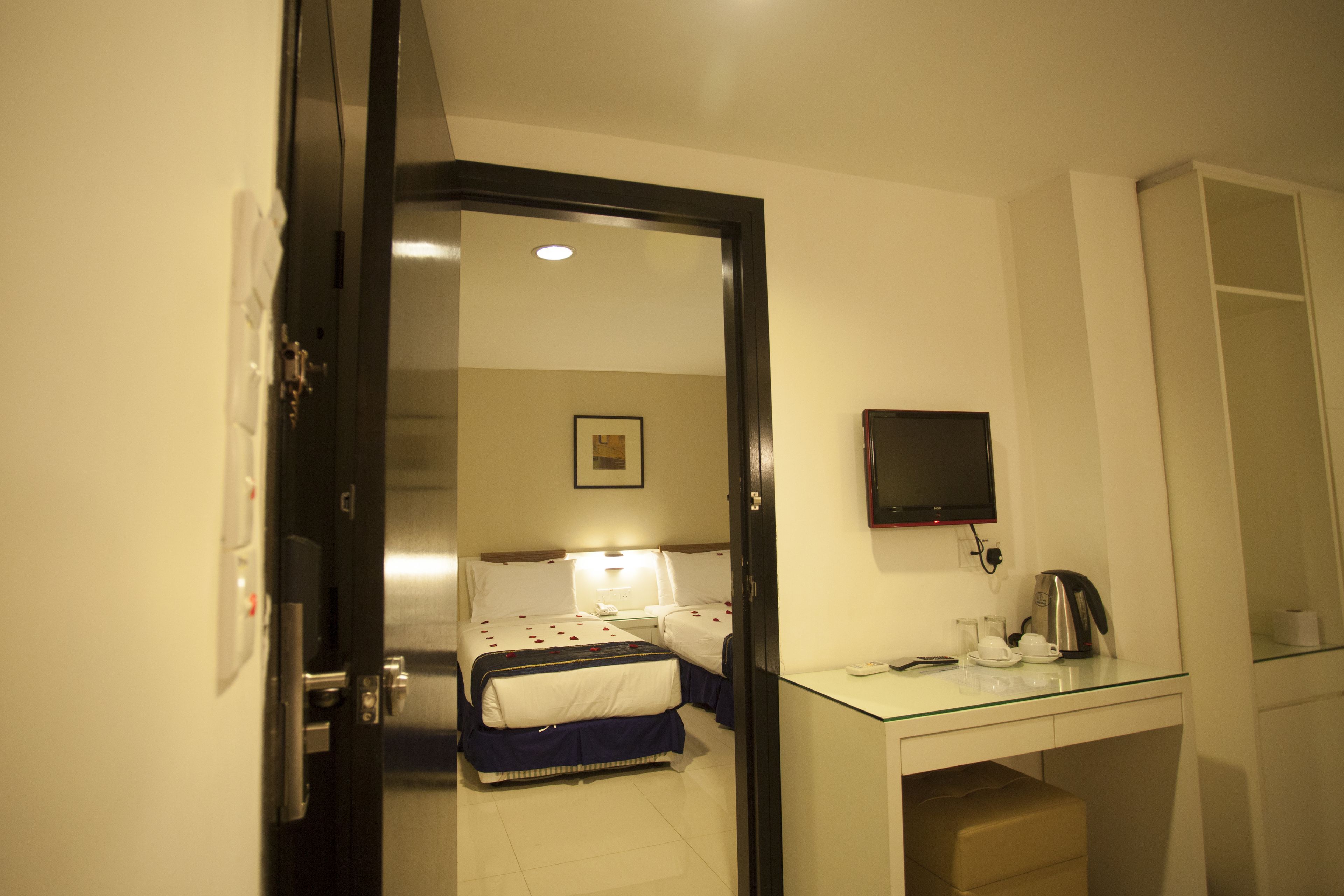 A hotel room with a bed, bedside table, and a TV mounted on the wall.