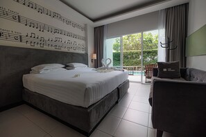 Een hotelkamer met een groot bed, een slaapbank, een balkon met uitzicht op groen en een muur met muzieknoten.