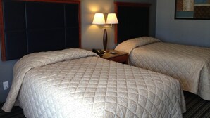 Habitació d'hotel amb dos llits, una tauleta de nit amb una làmpada i un quadre a la paret.