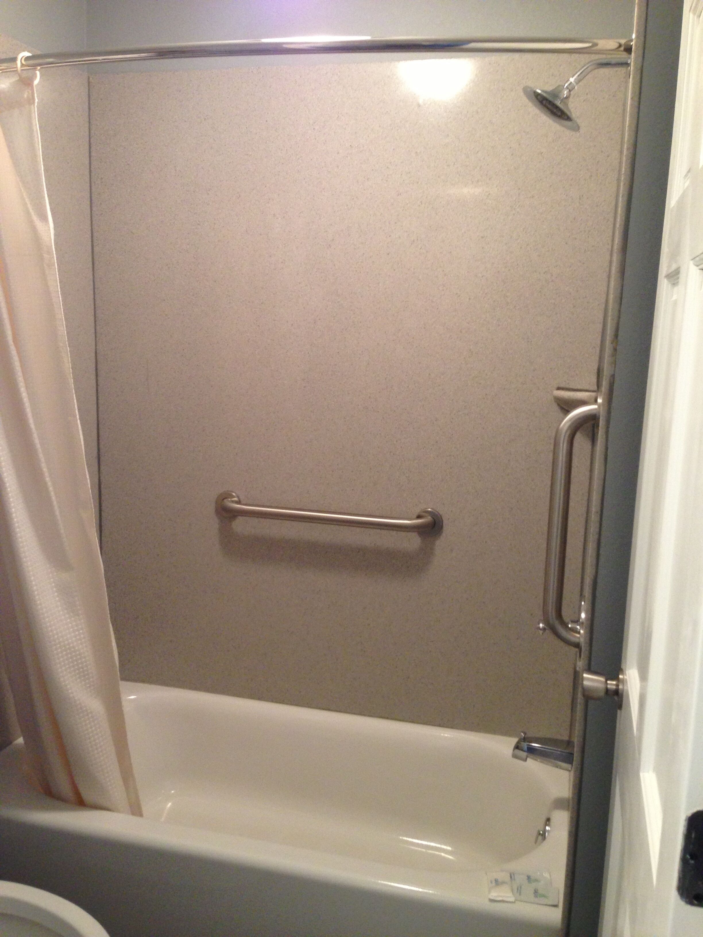 Un espace douche équipé d’une barre d’appui, d’un pommeau de douche et d’une baignoire.