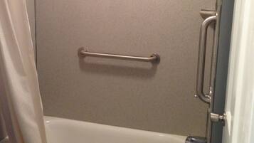 Un espace douche équipé d’une barre d’appui, d’un pommeau de douche et d’une baignoire.