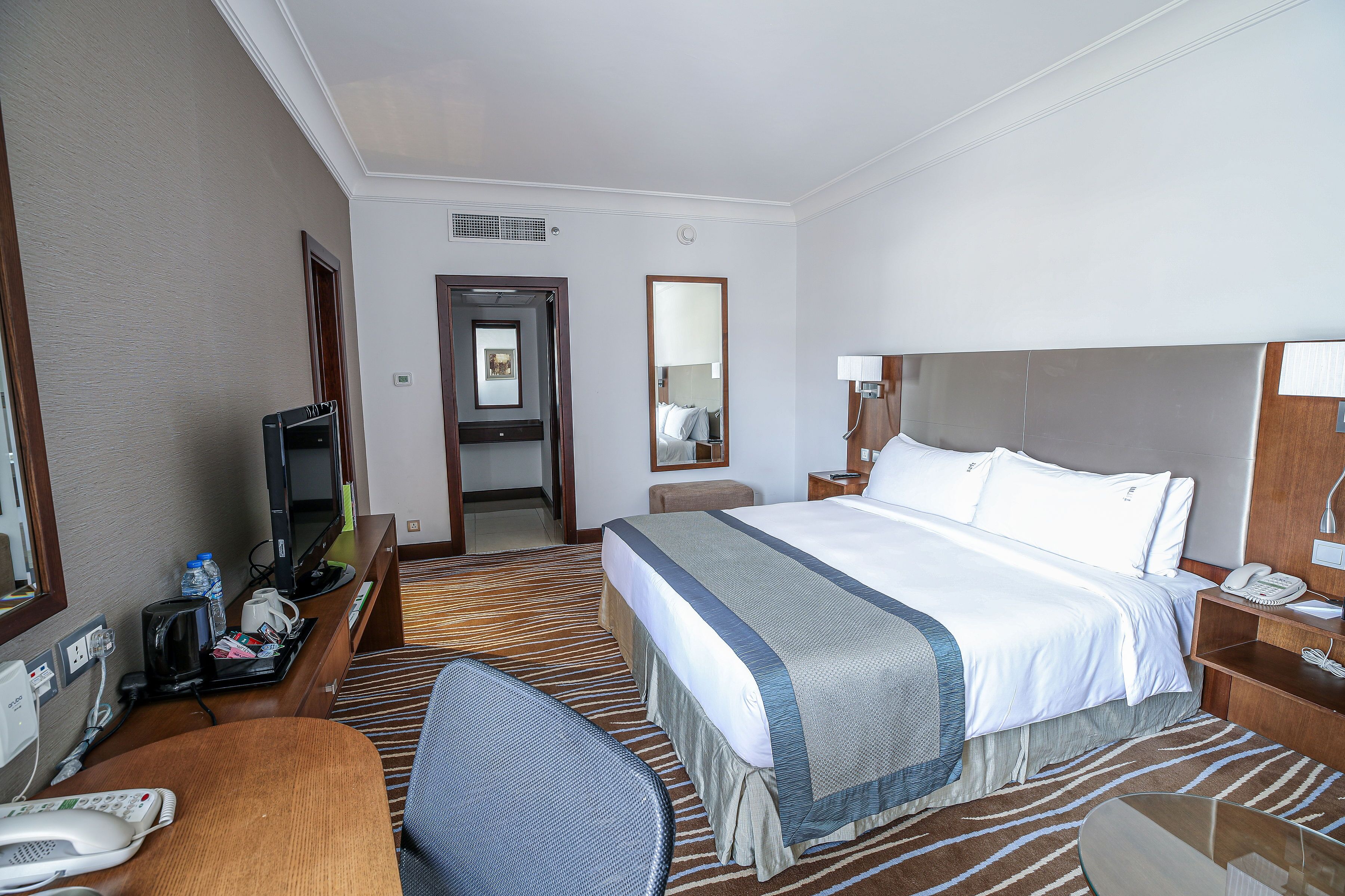 Une chambre d’hôtel avec un grand lit, un bureau avec un téléphone, une chaise et un téléviseur.