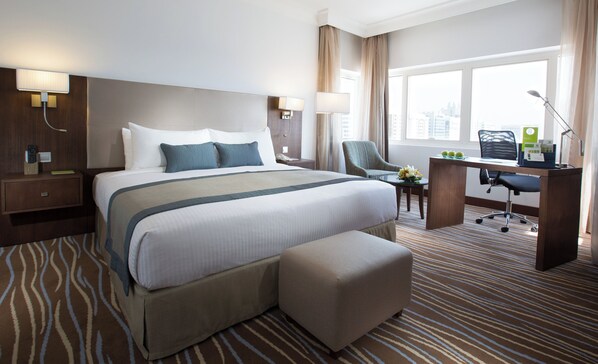 Habitación de hotel con una cama grande, un escritorio, una silla y vistas a la ciudad.