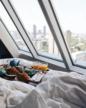 A bed with a city view, breakfast items, and a window with a cityscape. - Montcalm East, Autograph Collection (London)