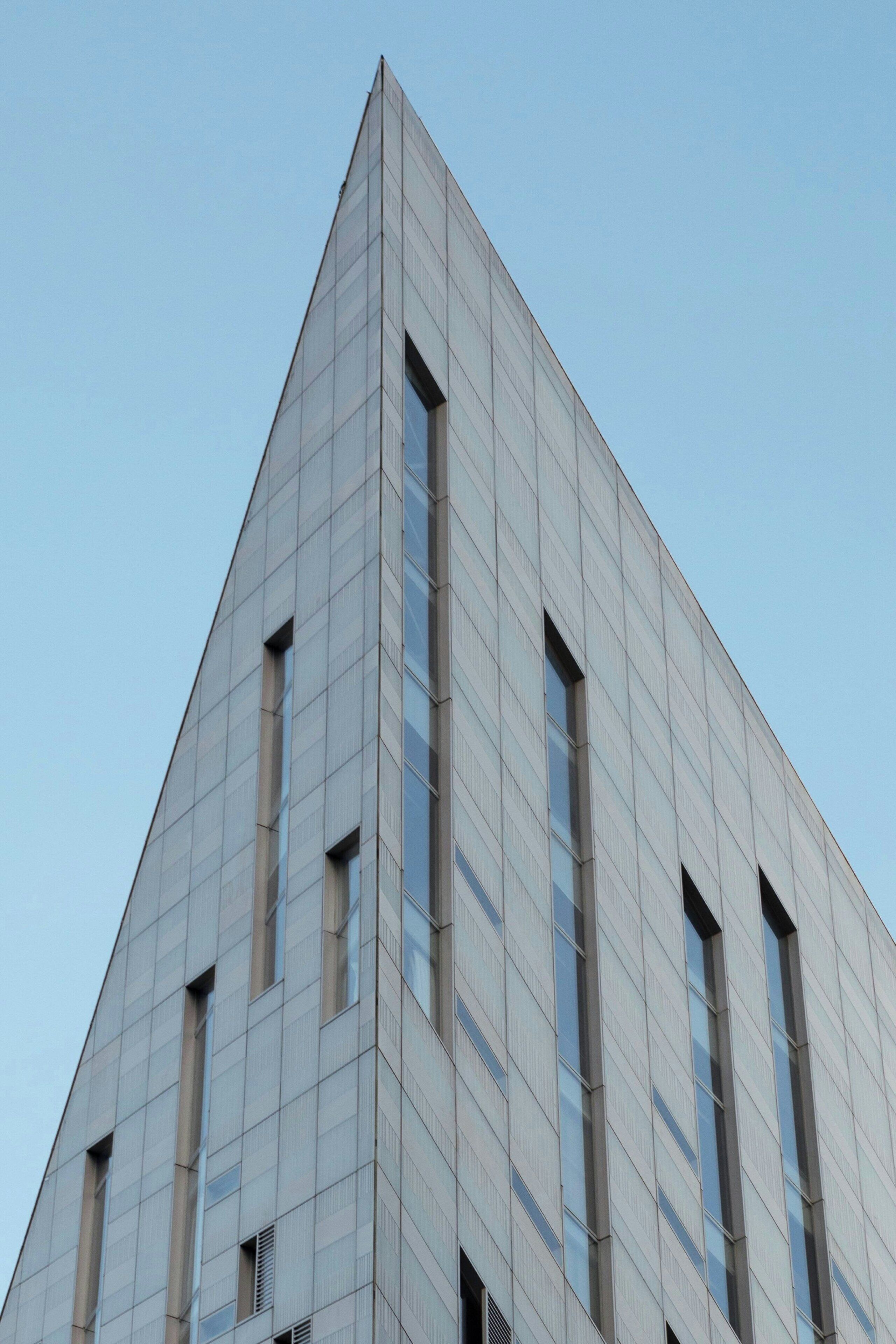 Un edificio moderno con fachada triangular y varios ventanales verticales.