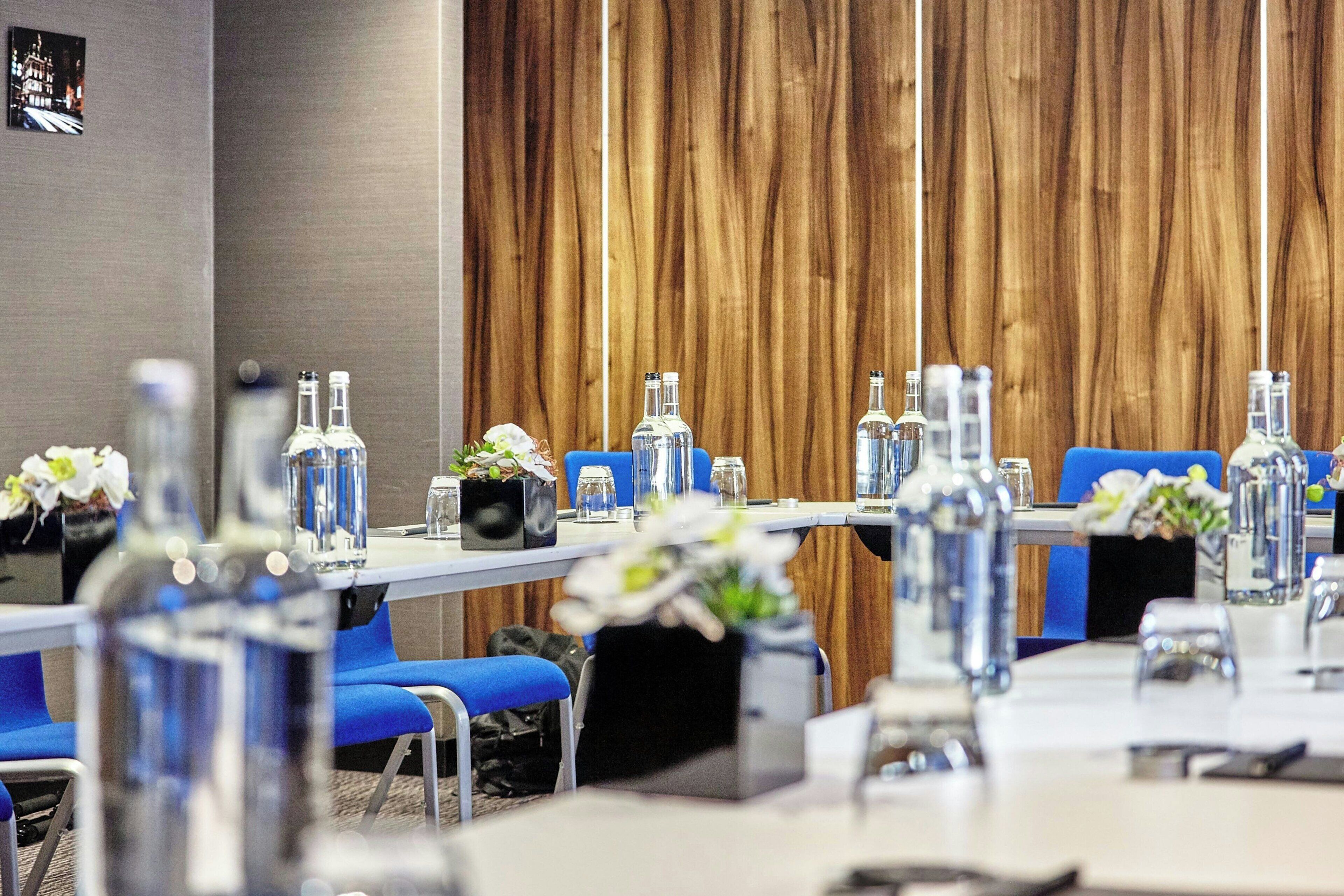 A conference room with long tables, chairs, and water bottles.