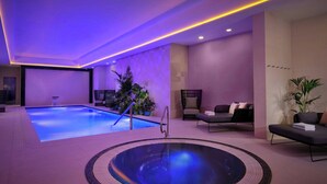 A modern indoor pool area with a hot tub, lounge chairs, and potted plants. - Montcalm East, Autograph Collection (London)