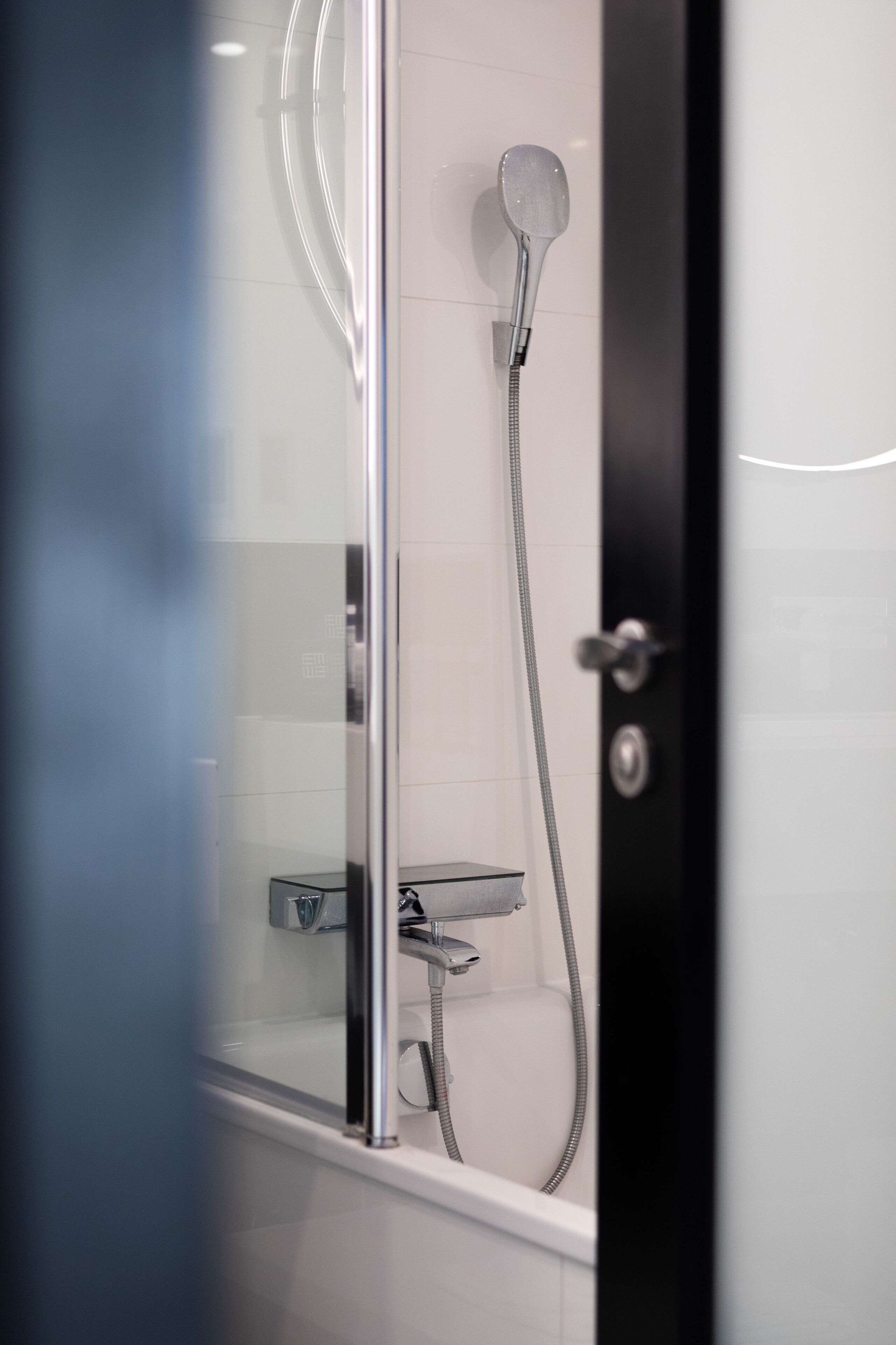 A modern shower with a handheld showerhead and a wall-mounted faucet.