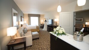 Une chambre d’hôtel équipée d’un lit, d’un bureau, d’une télévision, d’un mini-bar et d’une grande fenêtre.