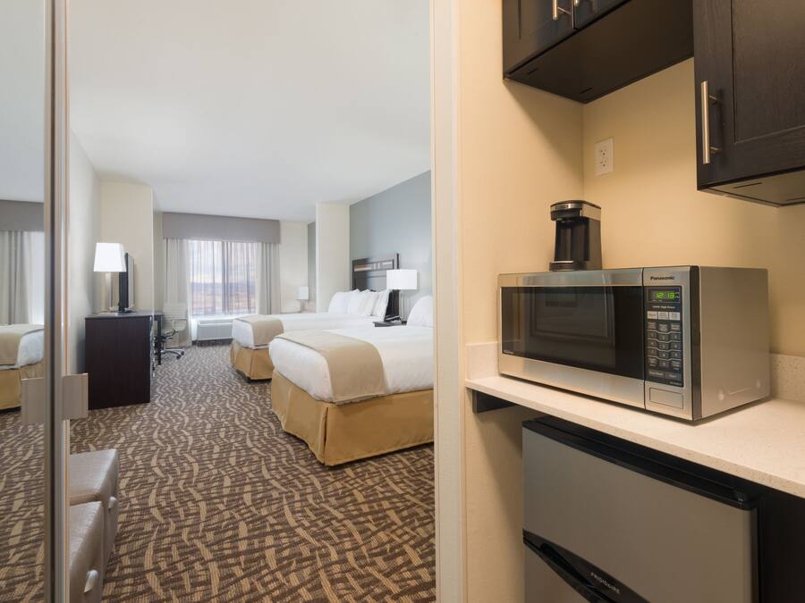 A hotel room with a bed, a desk, a microwave, and a refrigerator.