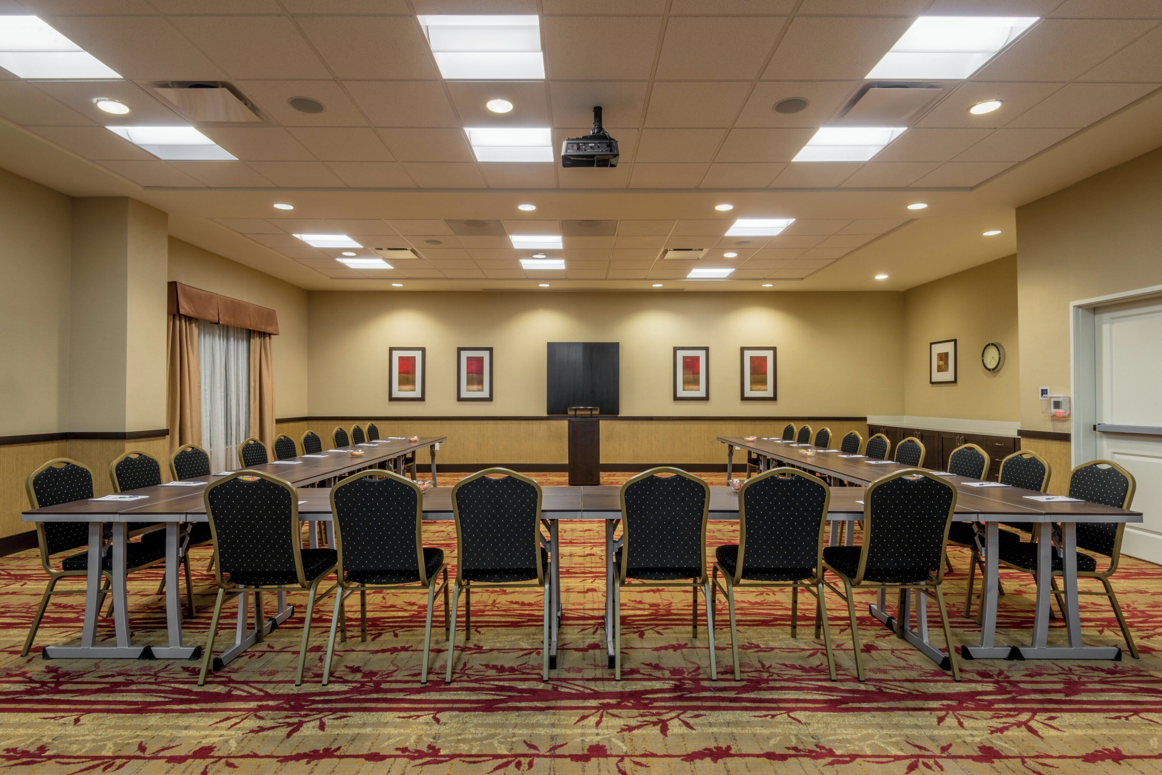 A conference room with a long table, chairs, a projector, and framed pictures on the wall.