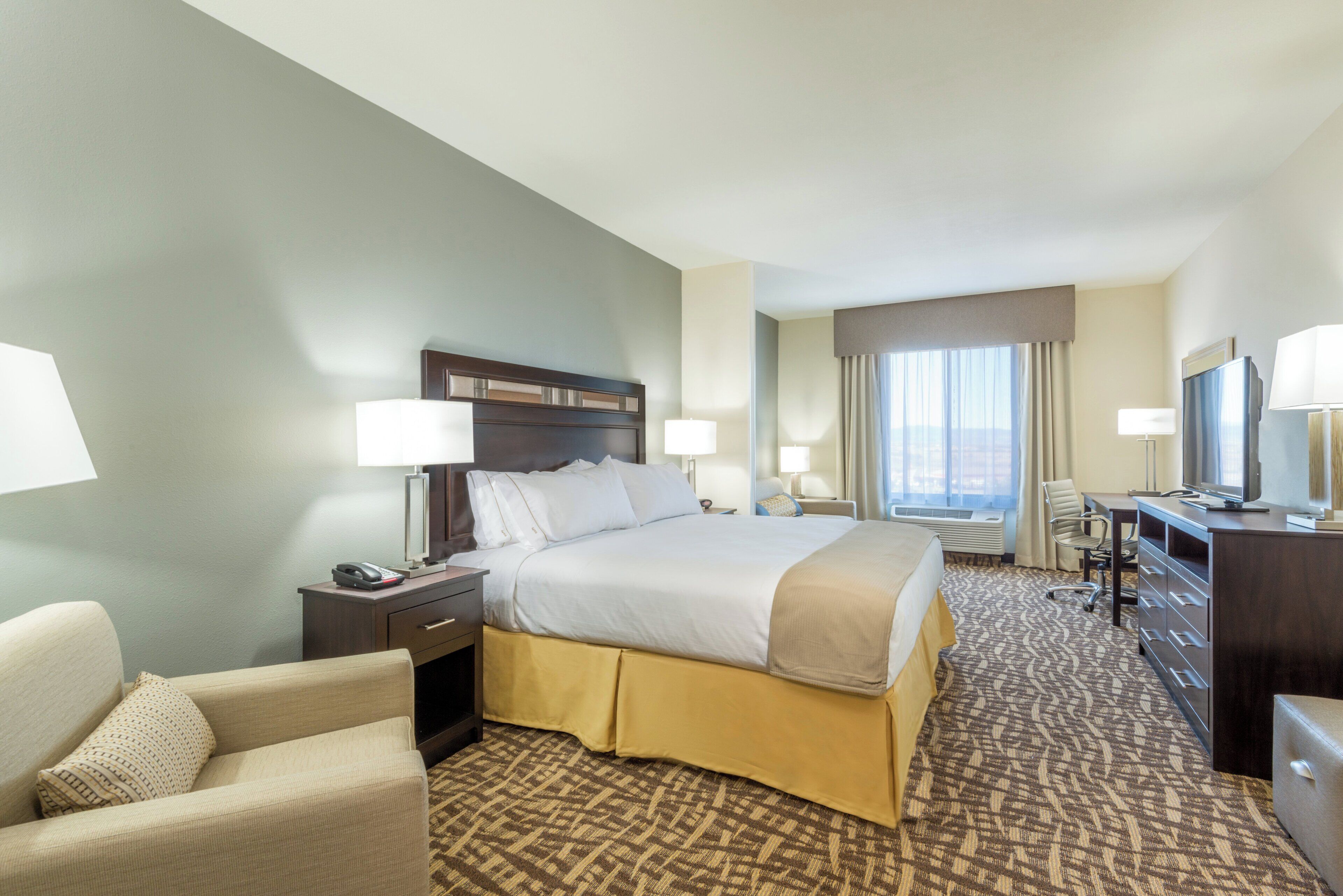 Une chambre d’hôtel comprenant un lit, des tables de chevet, un bureau, une chaise et un téléviseur.