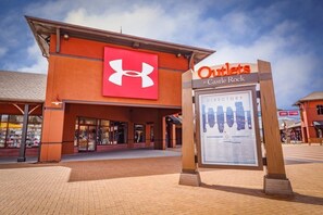 The exterior of a building with a prominent Under Armour logo and an Outlets sign at Castle Rock. - Holiday Inn Express & Suites Denver South - Castle Rock by IHG (Castle Rock)