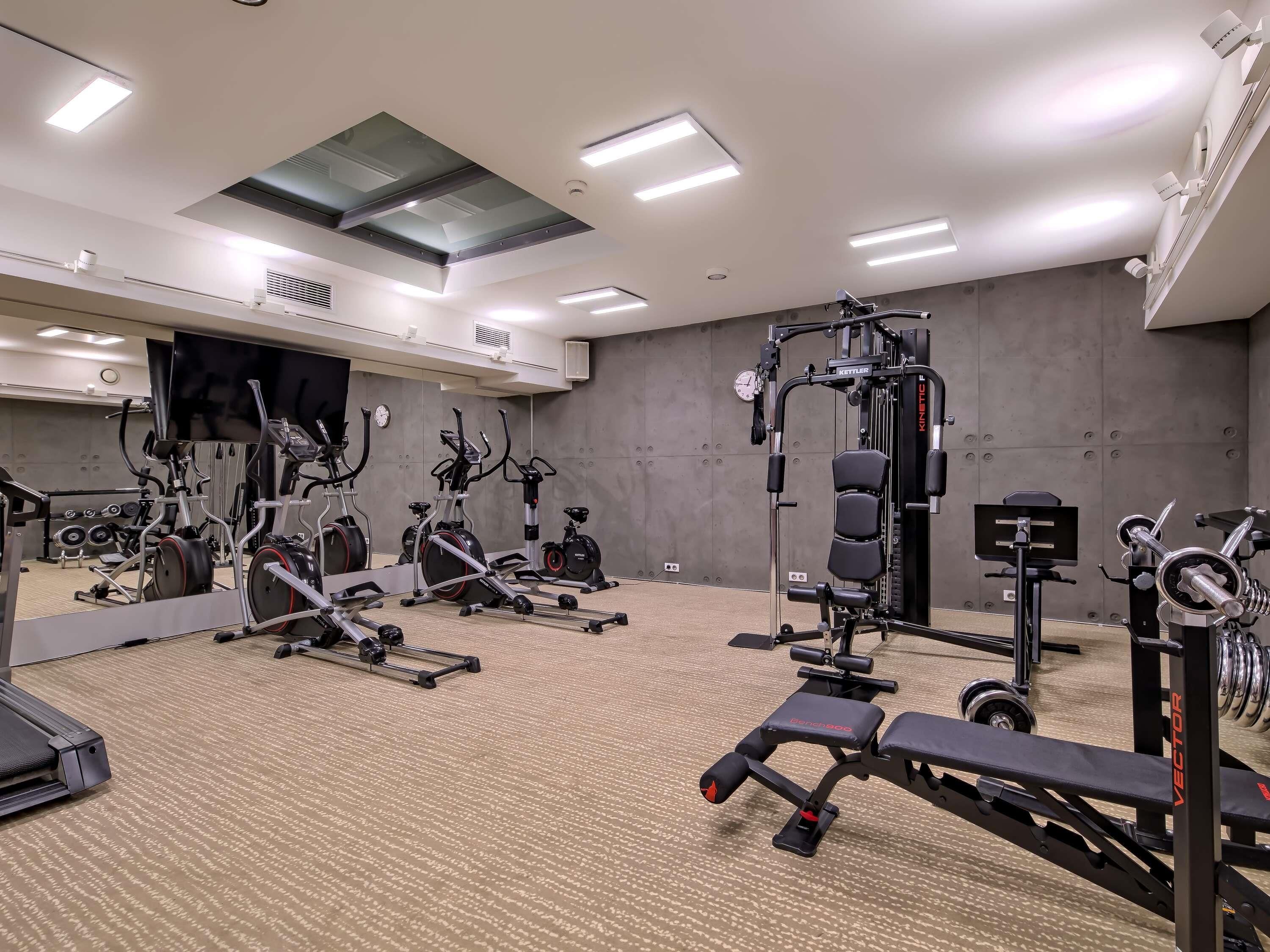 Un gimnasio con diversos equipos de ejercicio, como cintas de correr, bicicletas estáticas y máquinas de pesas.