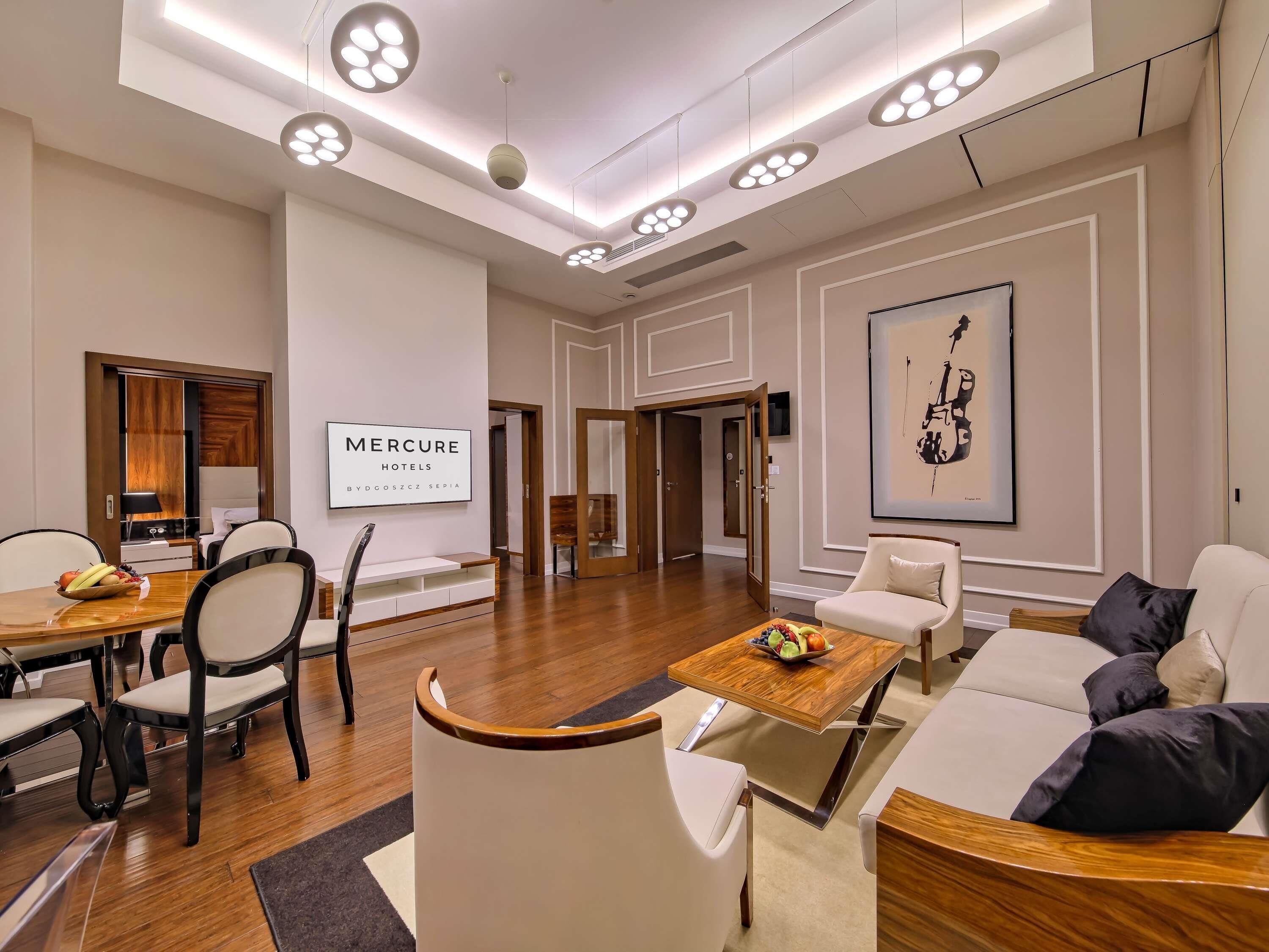 A modern hotel lobby with a dining area, a sofa, and a framed artwork on the wall.