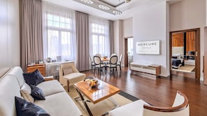 Een moderne hotelkamer met een bank, eettafel en groot raam.