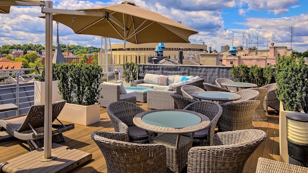 Een dakterras met rieten meubilair, een pooltafel en een grote parasol.
