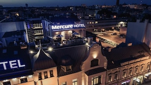 Een hotel met een opvallend bord, meerdere verdiepingen en een dak terras met buiten zitplaatsen.