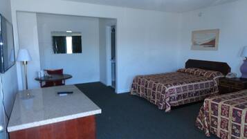 A hotel room with two beds, a desk, a chair, a small table, and a mirror.