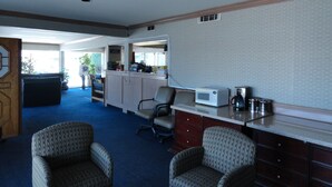 A hotel room with a kitchenette, two armchairs, a desk with a microwave, and a coffee maker. - Travel Inn (North Hills)