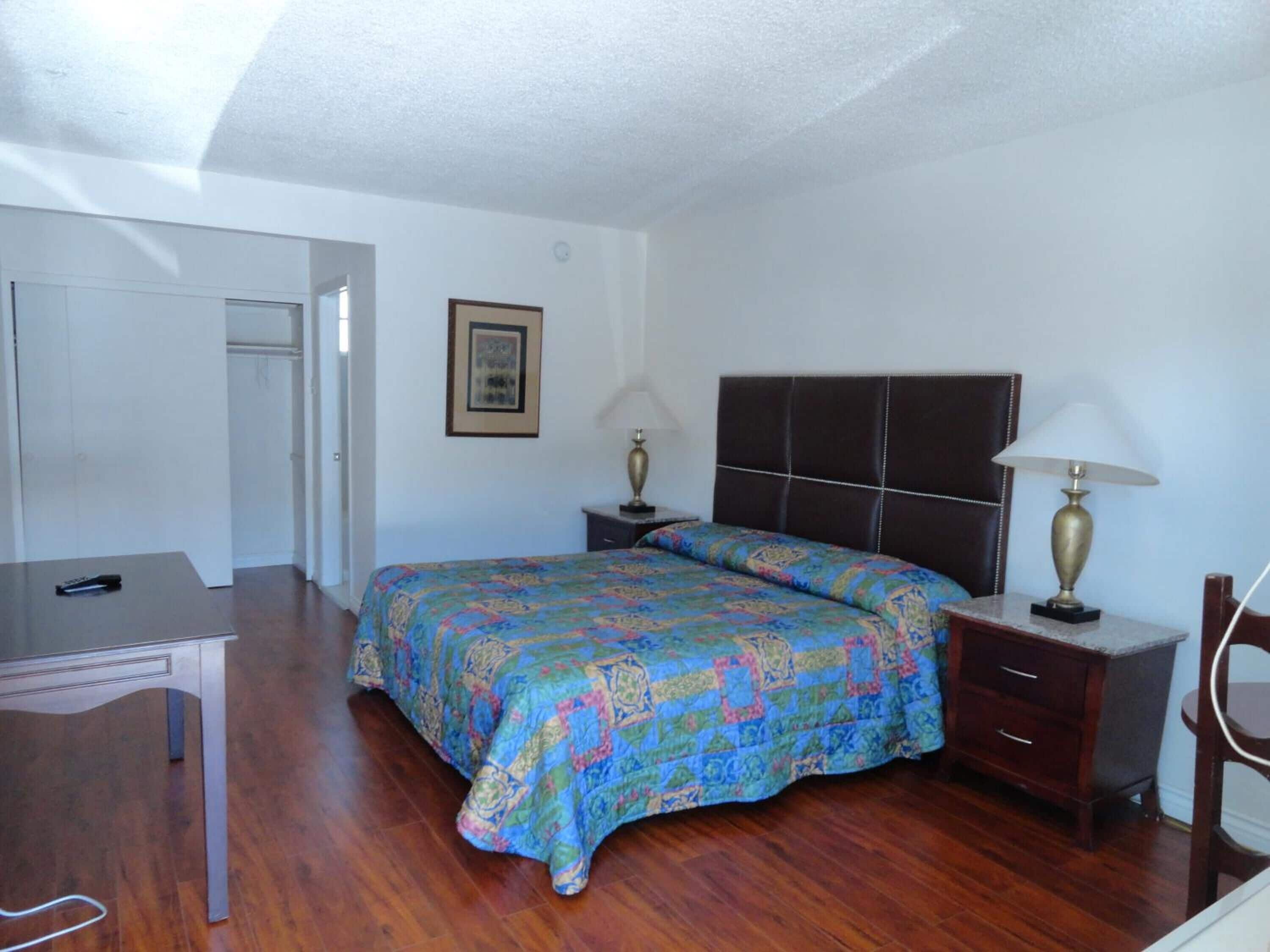 A bedroom with a bed, bedside tables, a desk, and a chair.