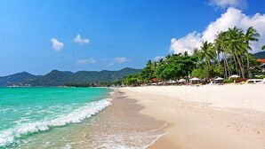 A beach with turquoise water, white sand, and palm trees.