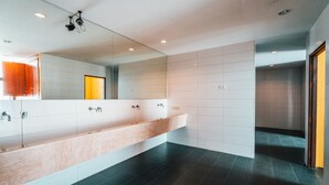 A modern bathroom with a large mirror, a long vanity, and dark tiled flooring.
