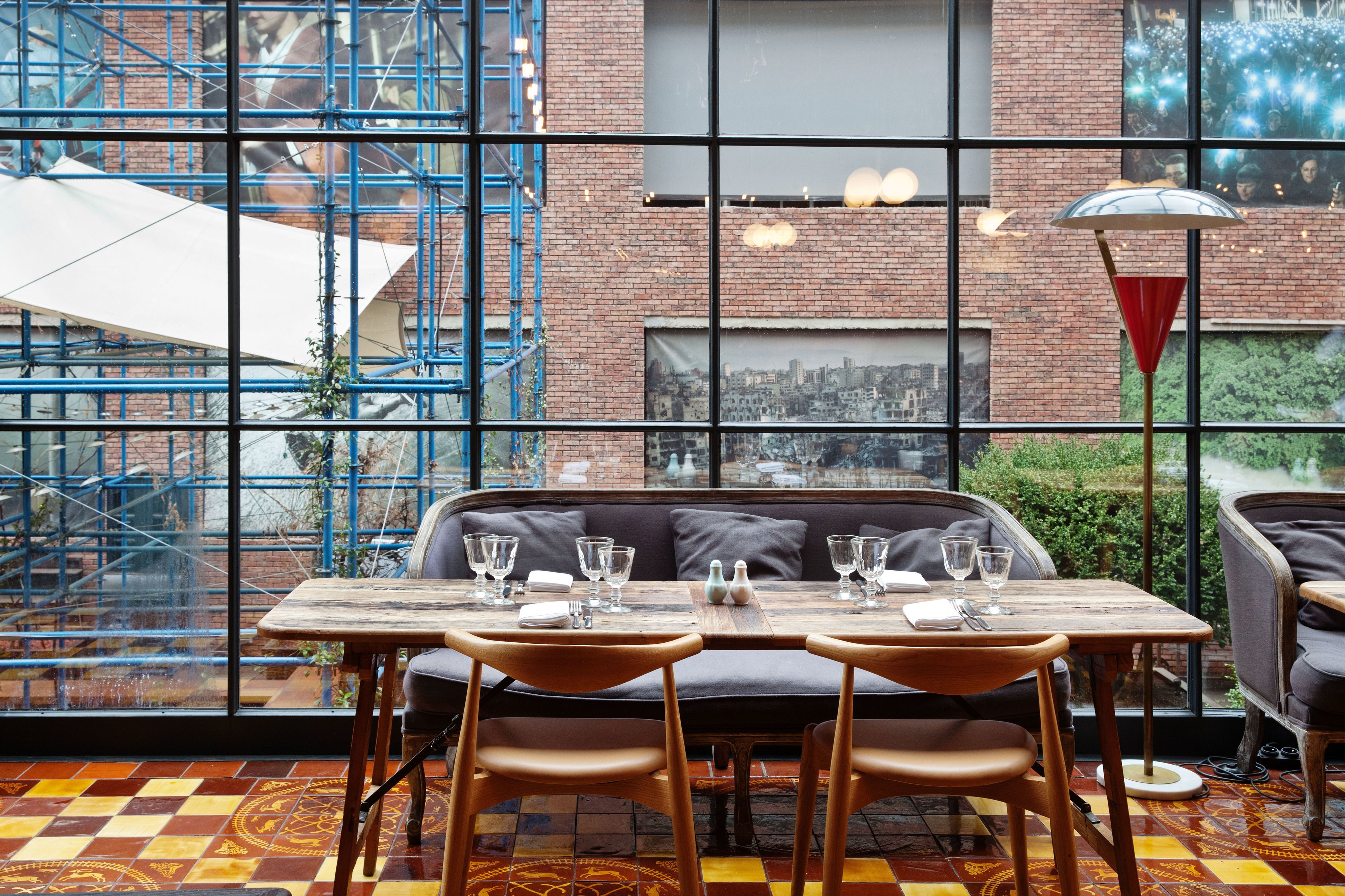 A restaurant with a large window view of a cityscape, a brick wall, and blue scaffolding outside.
