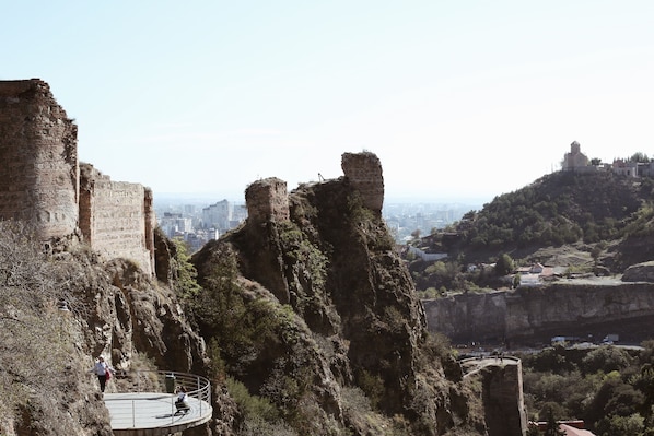 A historical site with ancient ruins, a circular viewing platform, and a distant view of a cityscape. - Rooms Hotel Tbilisi (Tbilisi)