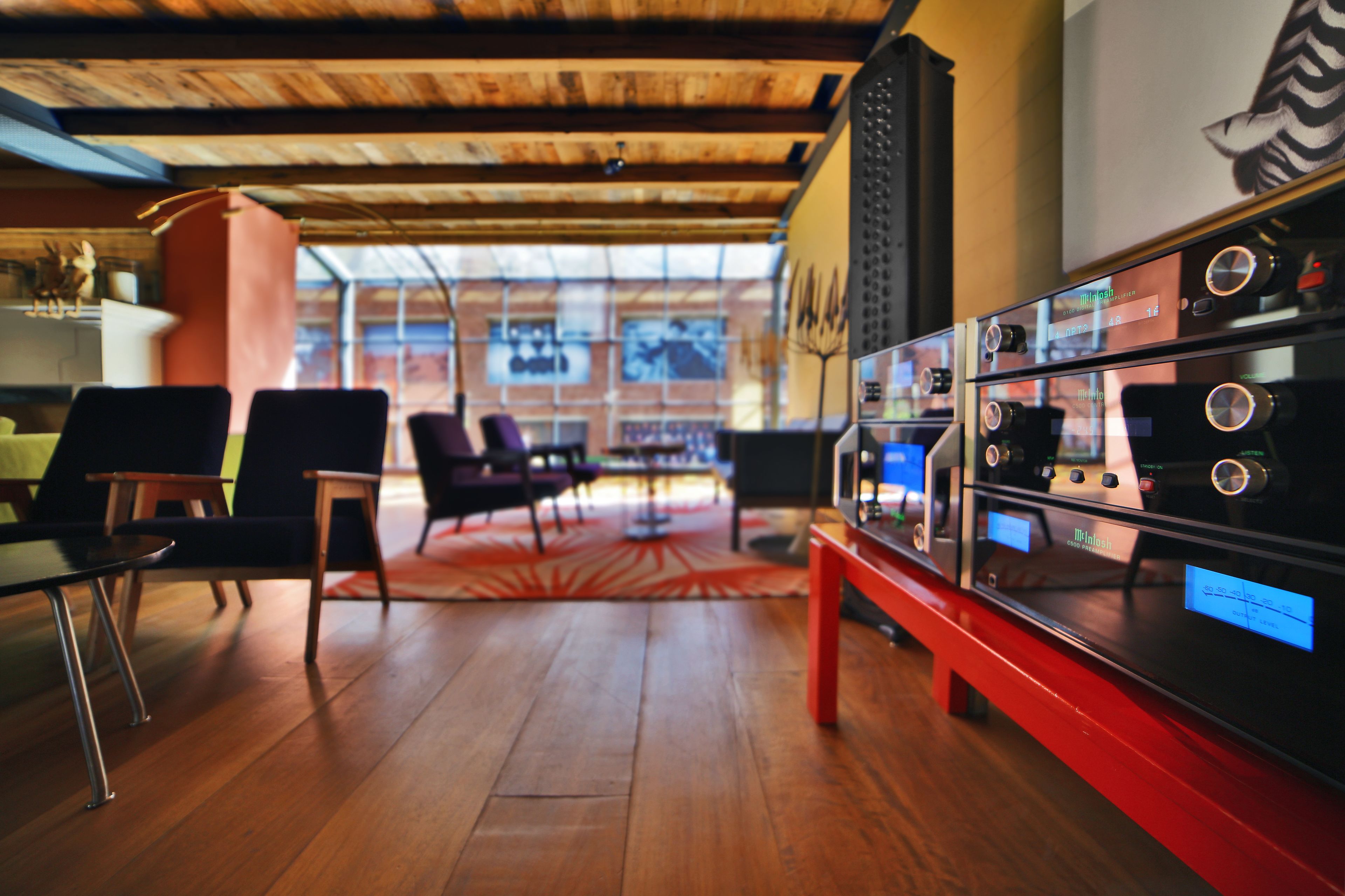 Un interior moderno con suelo de madera, un banco rojo y un sistema de sonido negro.