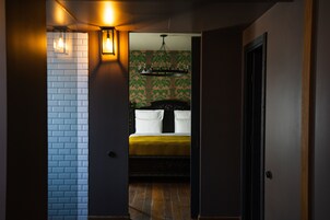 Un pasillo que conduce a un dormitorio con cama, candelabro y papel tapiz estampado.