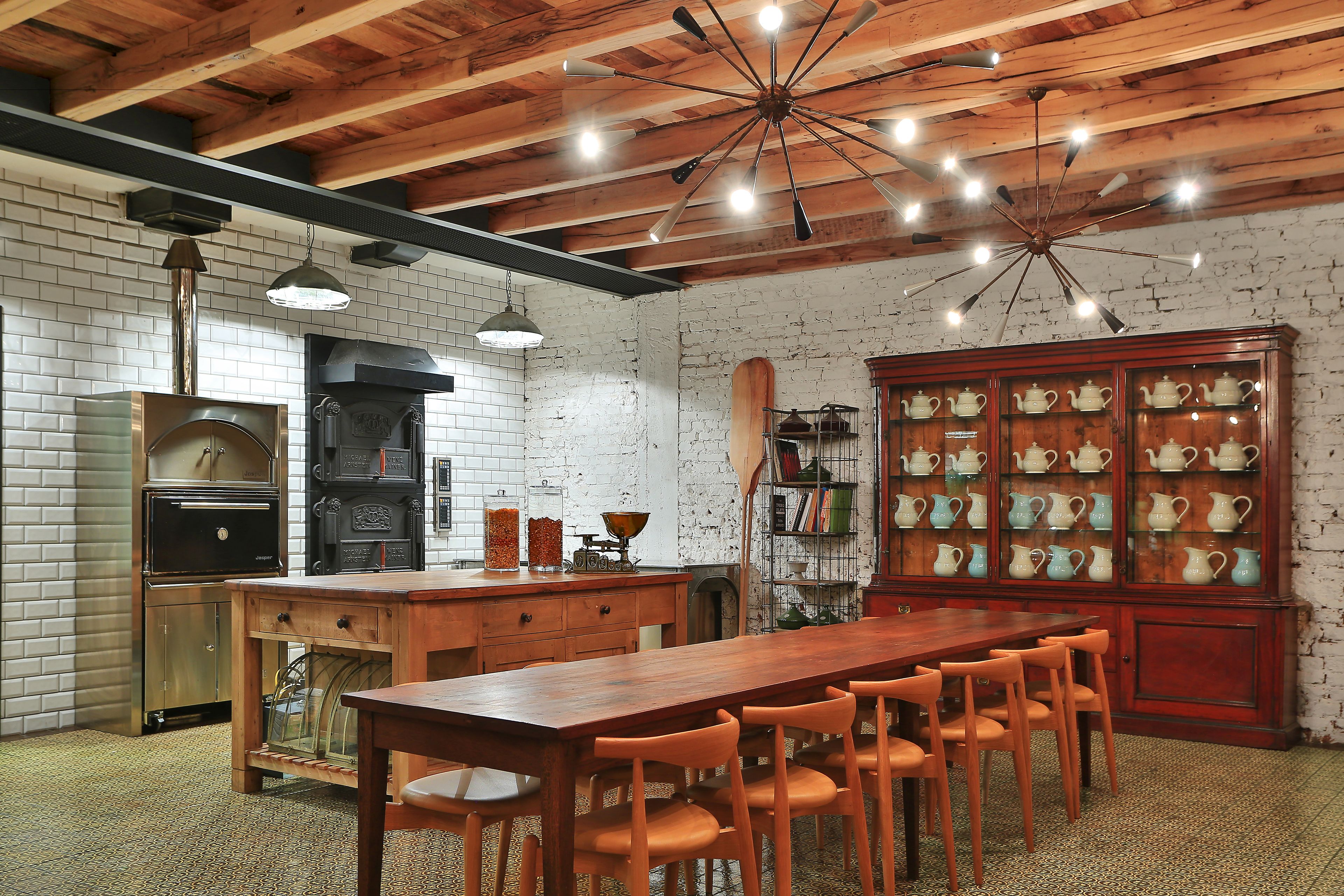 Una cocina rústica con vigas de madera a la vista, pared de ladrillo y una mesa de comedor de madera con sillas.